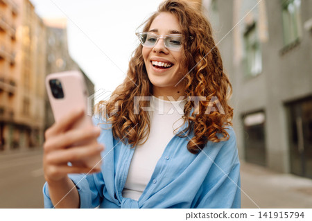 Portrait happy woman walking with phone in city. Online Communication with friend. Lifestyle concept Portrait happy woman walking with phone in city. Online Communication with friend. Lifestyle concept 141915794