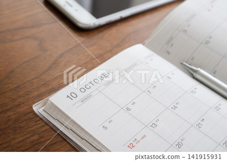 A schedule book and a smartphone on a wooden table A schedule book and a smartphone on a wooden table 141915931