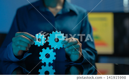 Asian businessperson holding a gear wheel over a laptop, symbolizing digital transformation, data strategy, workflow automation, innovation, and modern business technology. 141915998