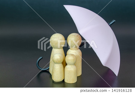 Wooden family figures beneath a red umbrella against a blue background illustrating protection, trust and insurance coverage 141916128