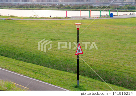 Slow Warning Sign on Riverside Lawn with Lamp Post in Quiet Green Park Slow Warning Sign on Riverside Lawn with Lamp Post in Quiet Green Park 141916234