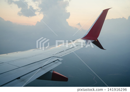 Airplane wing above the clouds at sunset, travel holiday aviation and journey background Airplane wing above the clouds at sunset, travel holiday aviation and journey background 141916296