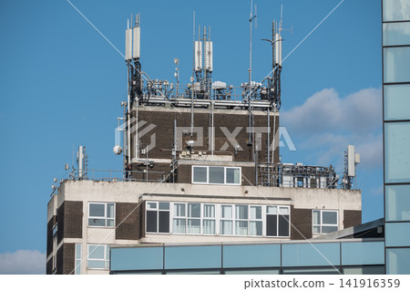 Corby, Northamptonshire, UK - August 2, 2026: Telecommunications antennas on rooftop of office building in Corby, England Corby, Northamptonshire, UK - August 2, 2026: Telecommunications antennas on rooftop of office building in Corby, England 141916359
