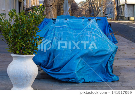 Blue tarpaulin hidden in street 141917099