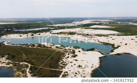 Showing industrial sand quarry pools, turquoise water glints amid white sands and green vegetation from above Showing industrial sand quarry pools, turquoise water glints amid white sands and green vegetation from above 141917352