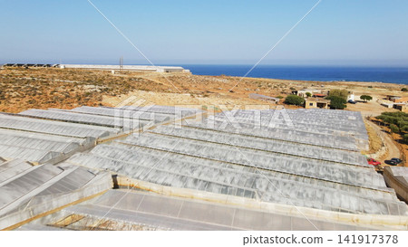 Greenhouses in a rural area next to the sea, showing extensive agricultural development on a sunny day in Greece Greenhouses in a rural area next to the sea, showing extensive agricultural development on a sunny day in Greece 141917378