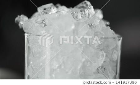 Crushed ice filling a clear glass, creating a refreshing frozen texture and cold beverage concept Crushed ice filling a clear glass, creating a refreshing frozen texture and cold beverage concept 141917380