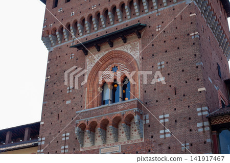 Tower Clock of Sforza Castle Brick Facade against Blue Sky in Milan City Center Italy Tower Clock of Sforza Castle Brick Facade against Blue Sky in Milan City Center Italy 141917467