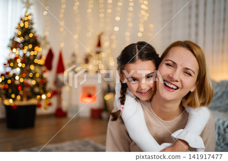 Mother and daughter embracing and smiling during Christmas holiday Mother and daughter embracing and smiling during Christmas holiday 141917477