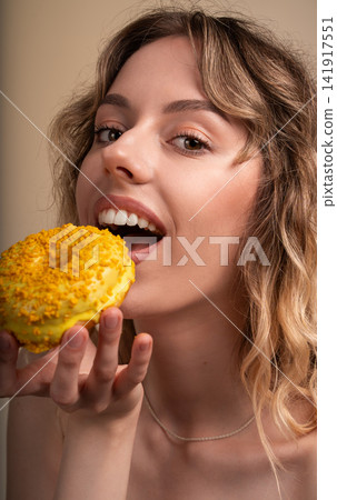 Young woman eating a delicious yellow glazed donut with sprinkles, enjoying sweet dessert and indulging in sugary treat Young woman eating a delicious yellow glazed donut with sprinkles, enjoying sweet dessert and indulging in sugary treat 141917551