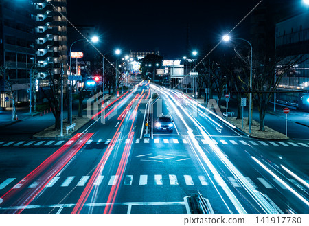 夜間汽車穿過馬路時留下的光跡,以及城市景觀。 夜間汽車穿過馬路時留下的光跡,以及城市景觀。 141917780