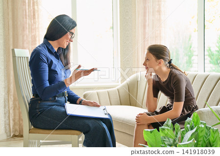 Child psychologist consulting a schoolgirl in office mental health therapy session Child psychologist consulting a schoolgirl in office mental health therapy session 141918039