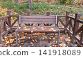 Wooden Park Bench Covered with Red and Yellow Autumn Leaves 141918089