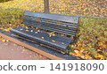 Wooden Park Bench Covered with Red and Yellow Autumn Leaves 141918090