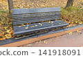 Wooden Park Bench Covered with Red and Yellow Autumn Leaves 141918091