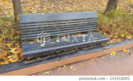 Wooden Park Bench Covered with Red and Yellow Autumn Leaves Wooden Park Bench Covered with Red and Yellow Autumn Leaves 141918091