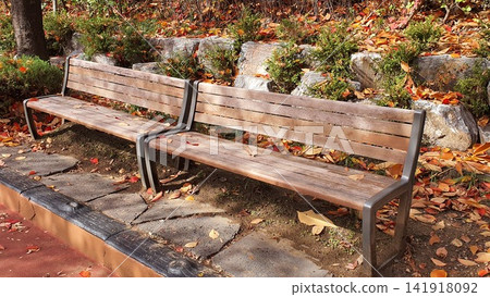 Wooden Park Bench Covered with Red and Yellow Autumn Leaves Wooden Park Bench Covered with Red and Yellow Autumn Leaves 141918092