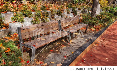 Wooden Park Bench Covered with Red and Yellow Autumn Leaves Wooden Park Bench Covered with Red and Yellow Autumn Leaves 141918093