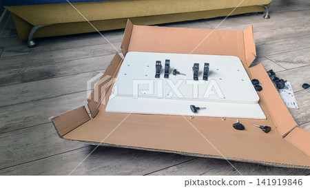 Flat pack furniture assembly components laid out in open box on wooden floor Flat pack furniture assembly components laid out in open box on wooden floor 141919846