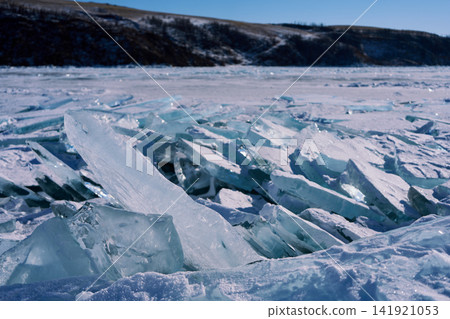 Transparent ice floes and snow-covered lake surface stretching across Lake Baikal in winter. Transparent ice floes and snow-covered lake surface stretching across Lake Baikal in winter. 141921053
