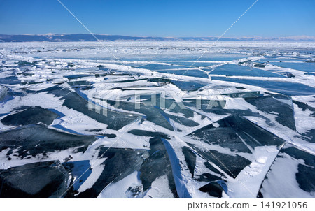 Lake Baikal and snow-capped mountains in winter, with layers of transparent ice. Lake Baikal and snow-capped mountains in winter, with layers of transparent ice. 141921056