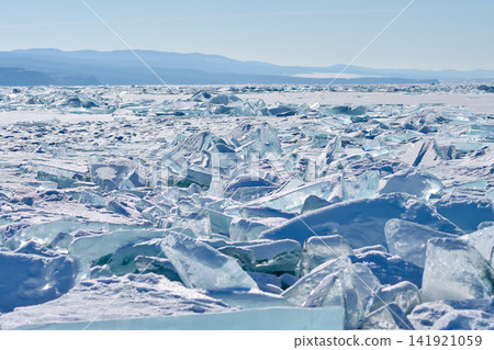 Lake Baikal in winter, with its transparent ice floes sparkling in the sunlight and distant mountain ranges in the background. Lake Baikal in winter, with its transparent ice floes sparkling in the sunlight and distant mountain ranges in the background. 141921059