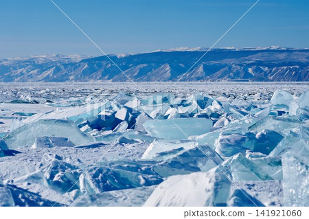 Frozen Lake Baikal and snow-capped mountains, with rows of blue ice floes. Frozen Lake Baikal and snow-capped mountains, with rows of blue ice floes. 141921060