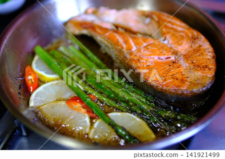 Step by step pan fried salmon steak recipe with fresh trout fillet seasoning oil and golden crust cooking process in black frying pan for homemade seafood meal Step by step pan fried salmon steak recipe with fresh trout fillet seasoning oil and golden crust cooking process in black frying pan for homemade seafood meal 141921499