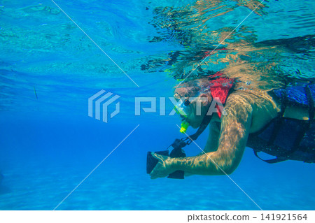 Man with photo camera taking photos and snorkeling underwater by coral reef in the Red sea, Egypt Man with photo camera taking photos and snorkeling underwater by coral reef in the Red sea, Egypt 141921564