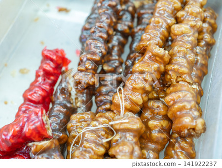 Delicious handmade churchkhela nut candies covered in grape and pomegranate juice jelly at a street market. Perfect visual for culinary travel guides, traditional sweets, and street food culture Delicious handmade churchkhela nut candies covered in grape and pomegranate juice jelly at a street market. Perfect visual for culinary travel guides, traditional sweets, and street food culture 141922237
