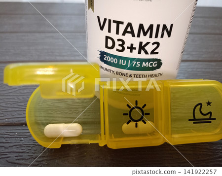 A medication organizer with vitamin D capsule in front of a supplement jar A medication organizer with vitamin D capsule in front of a supplement jar 141922257