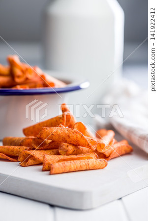 Close-Up Spicy Seasoned Snack Chips On Cutting Board With Bowl And Bottle In Soft Background 141922412