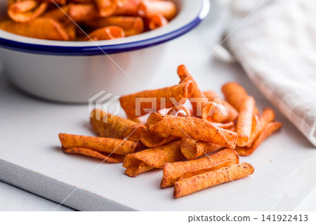 Close-Up Spicy Seasoned Snack Chips On Cutting Board With Bowl And Bottle In Soft Background Close-Up Spicy Seasoned Snack Chips On Cutting Board With Bowl And Bottle In Soft Background 141922413