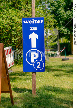 German directional parking sign on a wooden post showing the route to Parking P2. Perfect stock image for travel in Germany, event management, parking infrastructure, and road signs German directional parking sign on a wooden post showing the route to Parking P2. Perfect stock image for travel in Germany, event management, parking infrastructure, and road signs 141922427