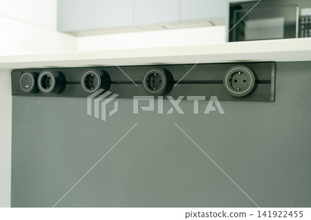 Built-in horizontal socket panel mounted into a kitchen counter for connecting domestic appliances. Perfect stock photo for kitchen ergonomics, home technology, and electrical hardware Built-in horizontal socket panel mounted into a kitchen counter for connecting domestic appliances. Perfect stock photo for kitchen ergonomics, home technology, and electrical hardware 141922455