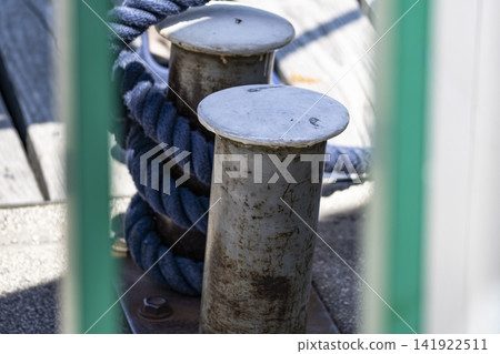 Blue braided rope wrapped around a metal mooring bollard at a marina, illustrating maritime work and dockside responsibilities. Blue braided rope wrapped around a metal mooring bollard at a marina, illustrating maritime work and dockside responsibilities. 141922511