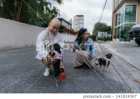 Women friends walking small pet dogs outdoors in city Women friends walking small pet dogs outdoors in city 141924367