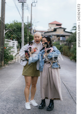 Two women taking street selfie with small dogs Two women taking street selfie with small dogs 141924372