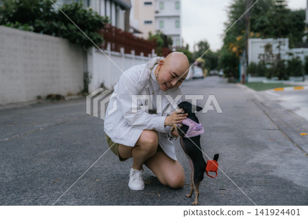 Woman kneeling, stroking small chihuahua dog on street Woman kneeling, stroking small chihuahua dog on street 141924401