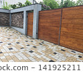 Modern House Exterior with Wooden Gate Brick Wall and Paved Driveway 141925211