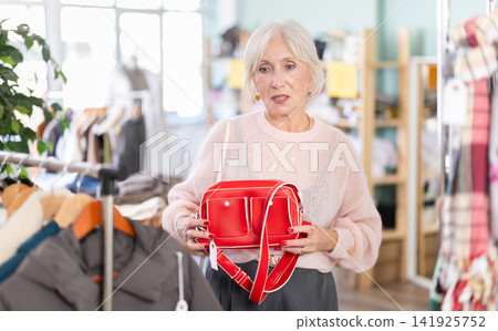 Mature woman choosing a fashionable handbag in store clothes 141925752