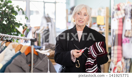Regular customer senior woman chooses color and style of sweater Regular customer senior woman chooses color and style of sweater 141925771