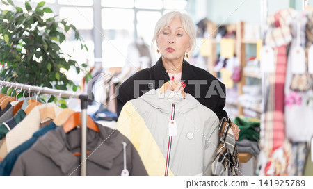 Regular customer mature woman chooses color and style of down jacket Regular customer mature woman chooses color and style of down jacket 141925789