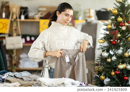 Armenian girl near showcase pick out and buying trousers, New Year eve Armenian girl near showcase pick out and buying trousers, New Year eve 141925809