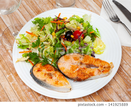 Two fried salmon steaks with vegetable salad Two fried salmon steaks with vegetable salad 141925889