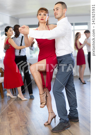 Woman in red and man in formal wear rehearsing tango in pair Woman in red and man in formal wear rehearsing tango in pair 141925931