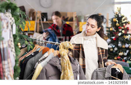 Young Armenian girl choosing coat in clothing store Young Armenian girl choosing coat in clothing store 141925956