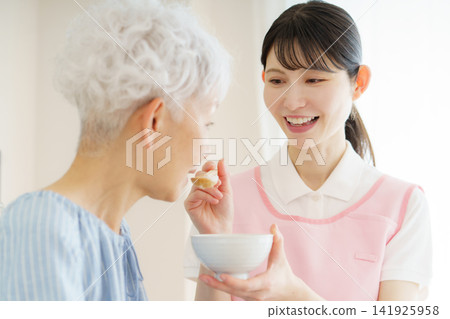 一位年輕的日本護士正在餵一位日本老婦人吃粥。 一位年輕的日本護士正在餵一位日本老婦人吃粥。 141925958