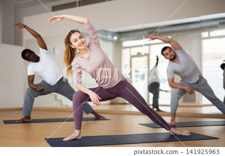 Woman doing Utthita Parsvakonasana during group yoga workout Woman doing Utthita Parsvakonasana during group yoga workout 141925963