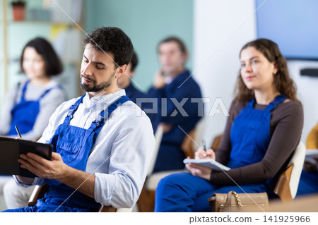 Young man worker listening to lecture and taking notes on tablet Young man worker listening to lecture and taking notes on tablet 141925966